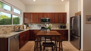 A modern kitchen with wooden cabinets, stainless steel appliances, and a granite countertop. - Capri Coastal Tuscan Getaway – Ideal for Extended Stays! (Encinitas)