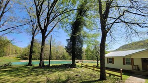 A rustic cabin with a gravel path leading to it, surrounded by trees and a lake. - Seek your rest at “Bertie’s Nest” (Parthenon)