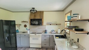 A modern kitchen with a refrigerator, stove, microwave, and sink. - Seek your rest at “Bertie’s Nest” (Parthenon)