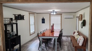 A dining area with a long wooden table, black chairs, and a bench. There is a black console table with kitchen appliances and a sign that reads "office bar". - Seek your rest at “Bertie’s Nest” (Parthenon)
