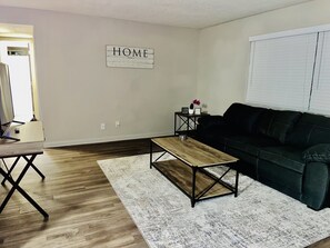 Relax in this stylish living room with a black leather sofa, wooden coffee table, and white rug.