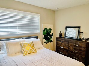 Relax in this serene bedroom with a comfortable bed, dresser, and natural views.
