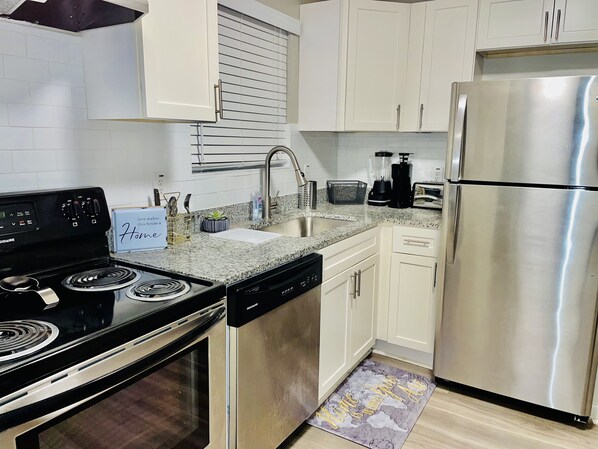 Enjoy cooking in this well-equipped kitchen with a black stove, dishwasher, and refrigerator.