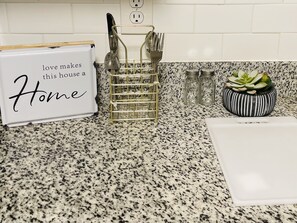Homey kitchen with a personal touch, featuring a sign, utensil holder, and a small succulent plant.