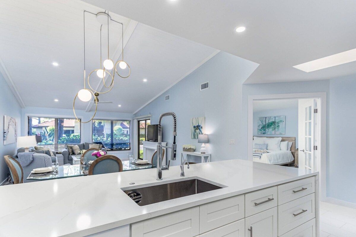 A modern kitchen with a large island, built-in appliances, and pendant lighting.