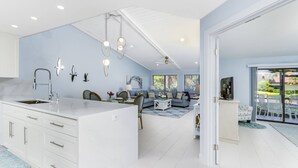 Une cuisine moderne avec des meubles blancs, un îlot central et des luminaires suspendus.