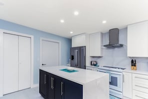 A modern kitchen with white cabinets, a central island, and a built-in oven. - Beach Paradise, Pool/Spa, Bright Updated Condo (Sarasota)