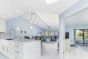 A modern kitchen with a central island, a dining area with a table and chairs, and a living room with a sofa and a coffee table. - Beach Paradise, Pool/Spa, Bright Updated Condo (Sarasota)