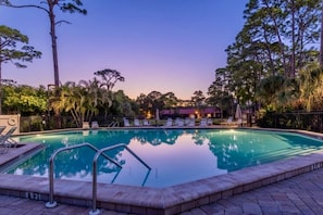A swimming pool with lounge chairs and a fence, surrounded by trees. - Beach Paradise, Pool/Spa, Bright Updated Condo (Sarasota)