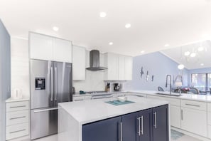 A modern kitchen with stainless steel appliances, white cabinetry, and a central island. - Beach Paradise, Pool/Spa, Bright Updated Condo (Sarasota)