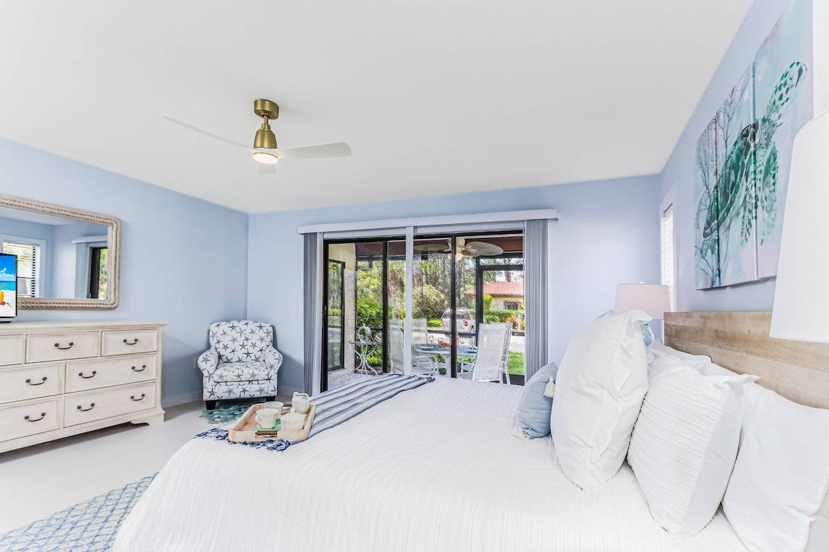 Une chambre à coucher avec un lit, une commode, une chaise et un ventilateur de plafond.