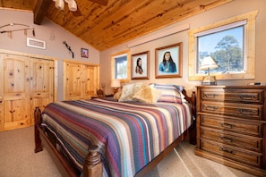 A bedroom with a wooden bed, a dresser, and a window with a view of trees.