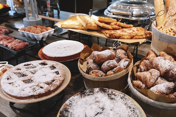 A buffet with various food items including pastries, bread, and desserts. - Novotel Belleville Paris 20 (Paris)