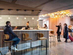Et moderne barområde med bardisk, siddepladser og en dekorativ loft.