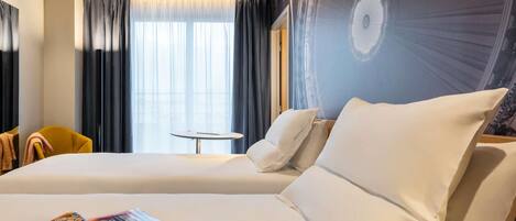 Una habitación de hotel con una cama grande, una mesita redonda y una silla.