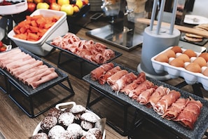 A buffet with various food items including meats, fruits, and pastries. - Novotel Belleville Paris 20 (Paris)