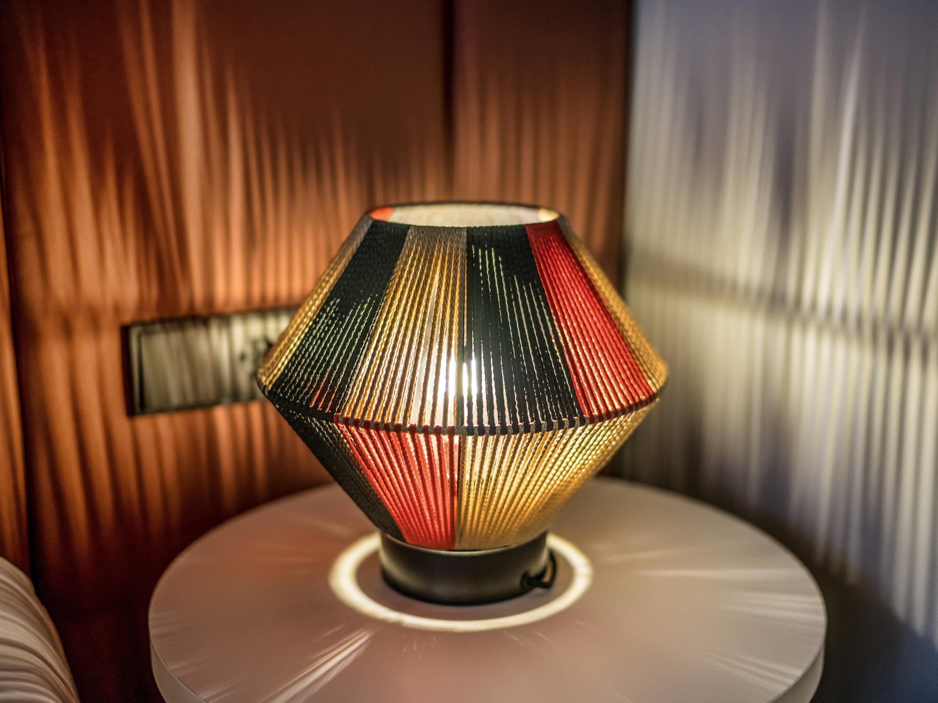 A lamp with a geometric design on a round table.