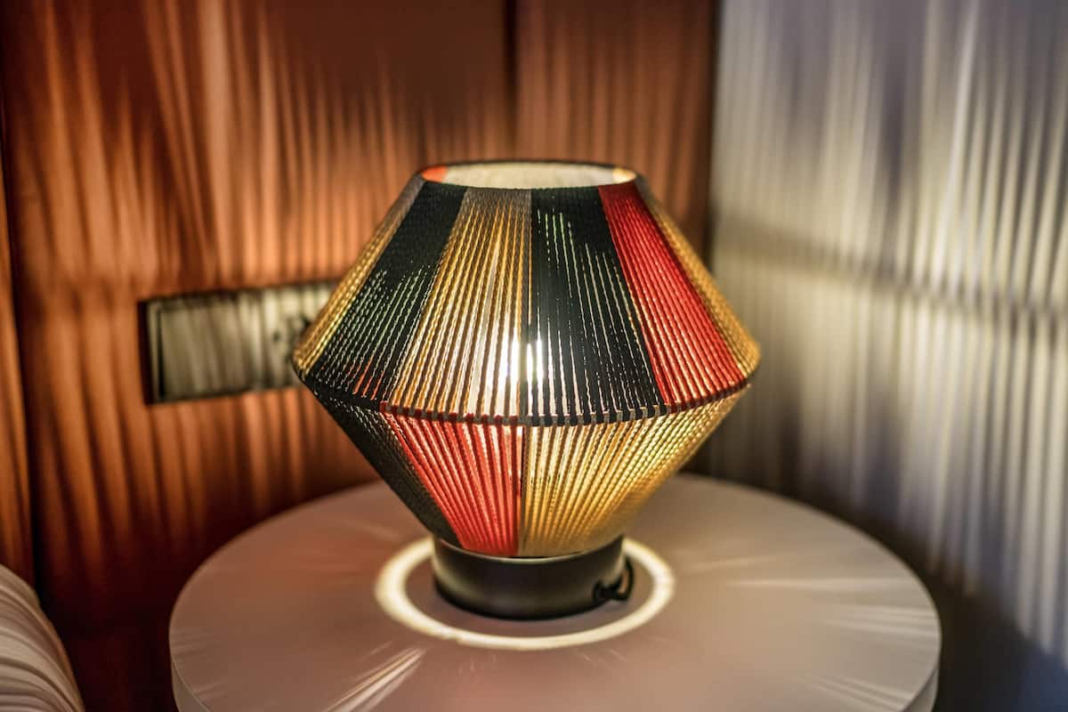 A lamp with a geometric design on a round table.