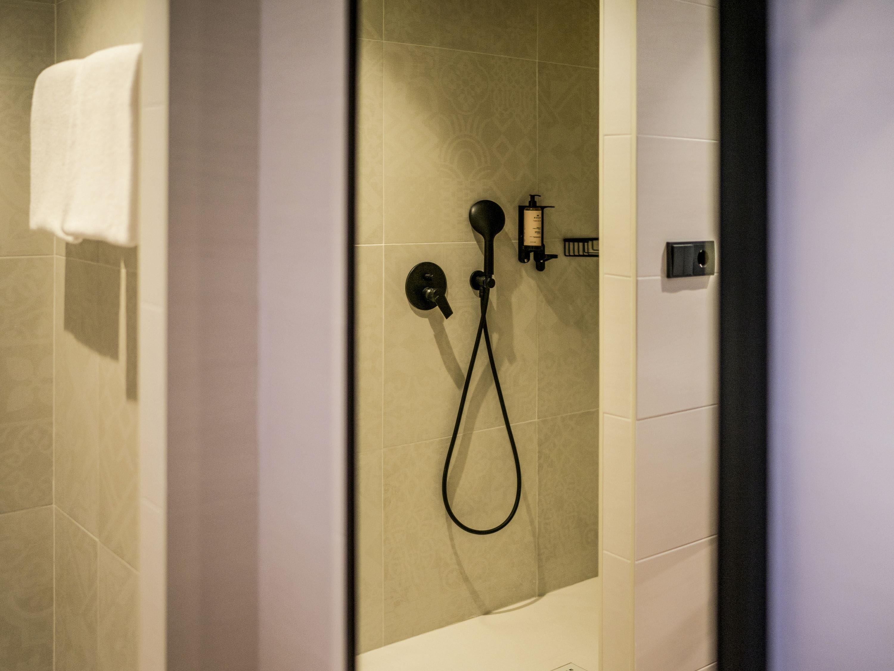 Un baño moderno con ducha, toallero y dispensador de jabón.