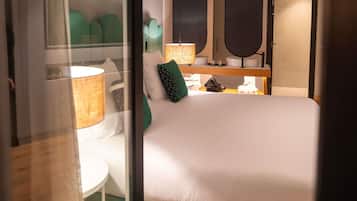 Habitación de hotel con cama, mesita de noche, lámpara y espejo.