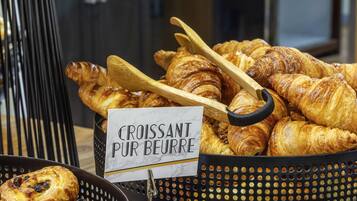 A display of croissants and other pastries in a basket with a sign reading "Croissant Pur Beurre".