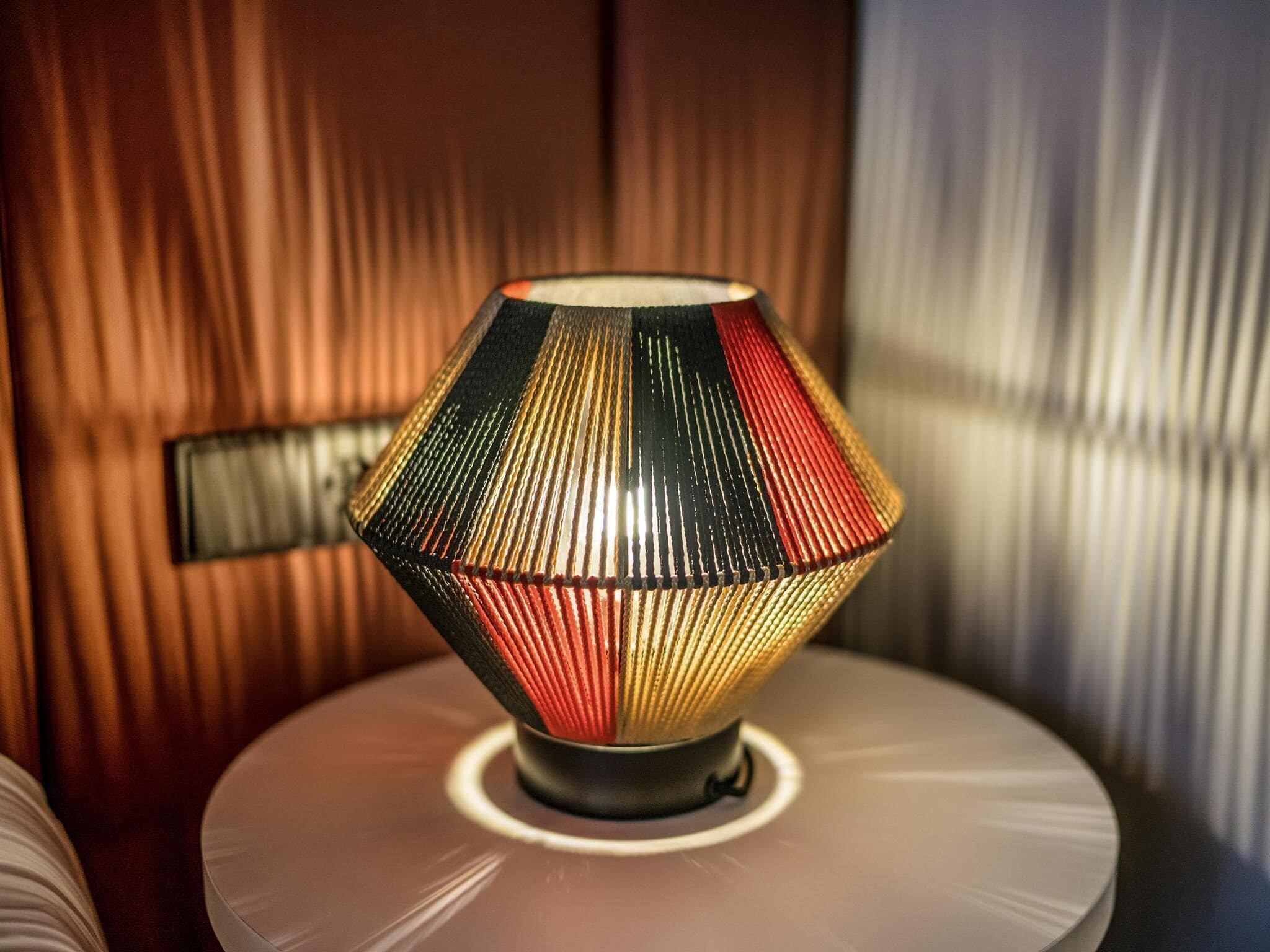 A lamp with a geometric design on a round table.