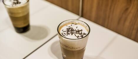 Dos vasos de café helado sobre una mesa blanca con fondo de madera.