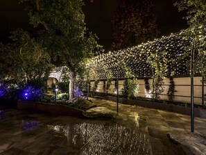 A nighttime outdoor area with a water feature, stone steps, and string lights. - Mercure Lugo Centro (Lugo)