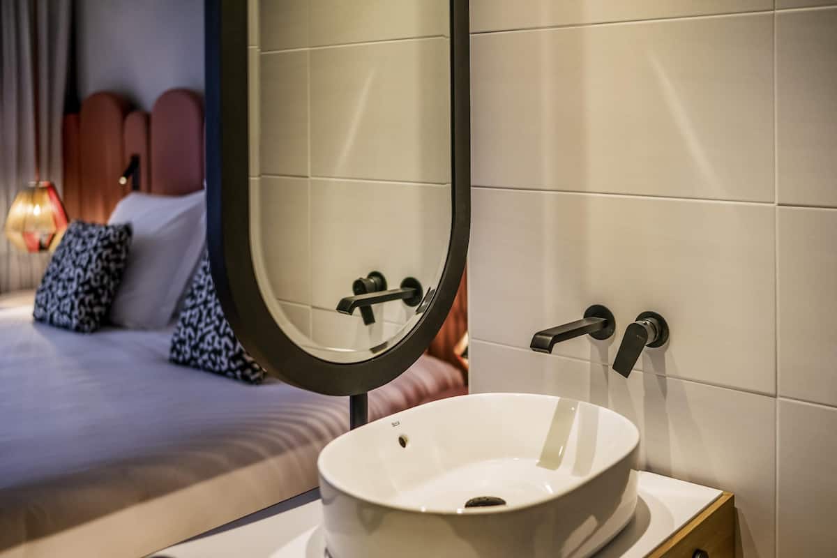 A modern bathroom with a round sink, a mirror, and a towel rack.