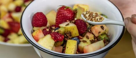 Una ensalada de frutas con una cucharada de granola.
