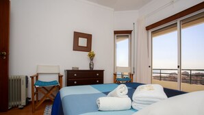 Een hotelkamer met een bed, een stoel, een dressoir, een spiegel en een raam met uitzicht.