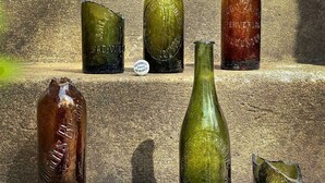Five glass bottles of varying shapes and sizes on stone steps.