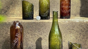 Five glass bottles of varying shapes and sizes on stone steps.