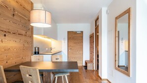 Een moderne keuken met houten details, een eethoek met stoelen, en een gang met een spiegel.
