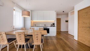 Een moderne keuken met witte kasten, een houten eettafel en stoelen.