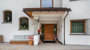 Een modern huis met een houten voordeur, een bankje en een klein portaaltje.