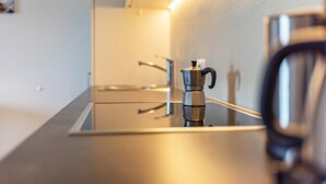Eine moderne Küche mit glatter Arbeitsplatte, einer Kaffeemaschine und einem Wasserkocher.