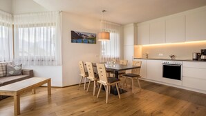 A modern kitchen with white cabinets, a dining table with chairs, a wooden bench, and a pendant light. - Apartment "Stefansdorf Wohnung 5" with Mountain View, Wi-Fi, Garden and Balcony (St. Lorenzen)