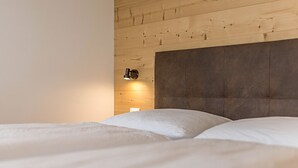 A bed with a headboard, a wall-mounted light, and a wooden panel wall. - Apartment "Stefansdorf Wohnung 5" with Mountain View, Wi-Fi, Garden and Balcony (St. Lorenzen)