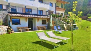 A two-story building with a stone facade, a balcony, and a small garden area with two sun loungers and a bench. - Apartment "Stefansdorf Wohnung 5" with Mountain View, Wi-Fi, Garden and Balcony (St. Lorenzen)