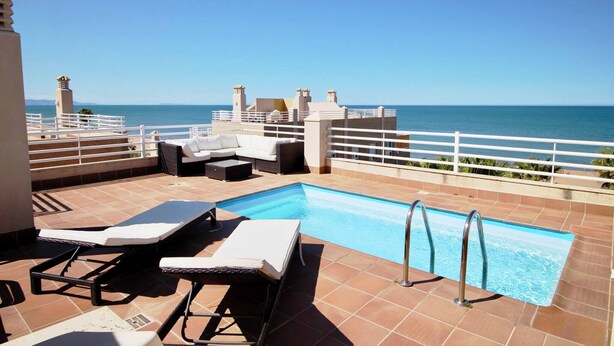 A rooftop pool with lounge chairs, a small table, and a view of the ocean. - El Amanecer 81 by homeprive (Denia)