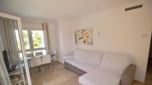 A modern living room with a sofa, a glass table, and a TV. - El Amanecer 81 by homeprive (Denia)