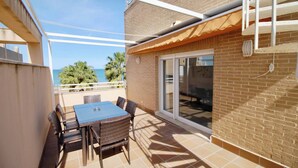 A patio with a table and chairs, a sliding glass door, and a view of the ocean. - El Amanecer 81 by homeprive (Denia)