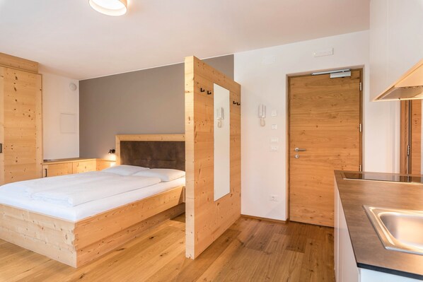 Une chambre moderne avec un lit en bois, une armoire en bois, une petite table de chevet et un banc intégré.