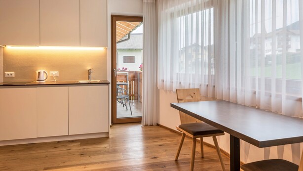 Une cuisine moderne avec un plan de travail en bois, une bouilloire et un évier. Il y a également un coin repas avec une table et des chaises.