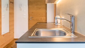 Une cuisine moderne dotée d’un évier en acier inoxydable, de lambris en bois et d’une porte avec un interrupteur.