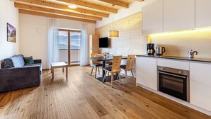 Una cocina moderna con vigas de madera, una zona de comedor con mesa y sillas, y un sofá.