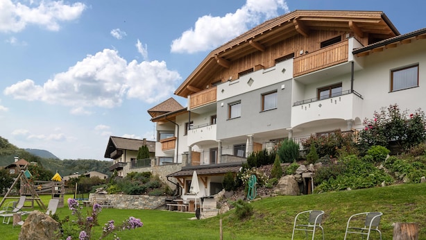 A multi-story building with balconies, a play area, and a garden.