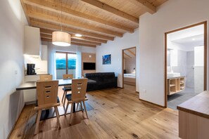 A modern interior with a dining area, kitchen, and a view of the outdoors.