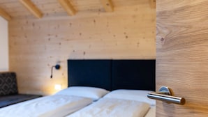 A wooden ceiling, a bed with white bedding, and a door with a metal handle.